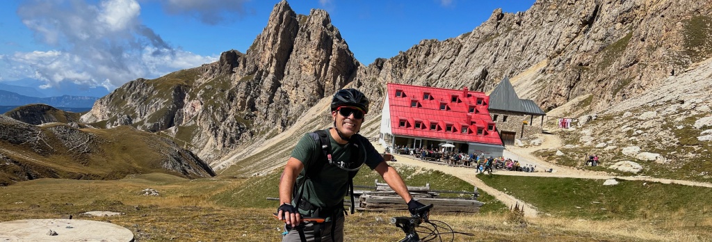 Gerardo standing with his bike in front of a rifugio in the Dolomites
